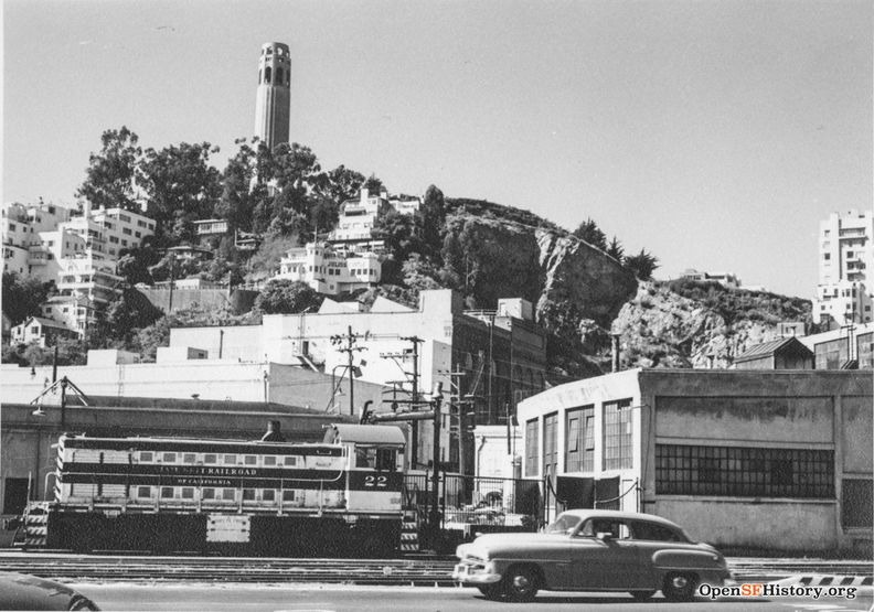 C1957 View west from The Embarcadero near Lombard toward Telegraph Hill. Belt Line locomotive 22 and Belt Line Railroad roundhouse at right, Julius Castle and Coit Tower in the background wnp27.3268.jpg