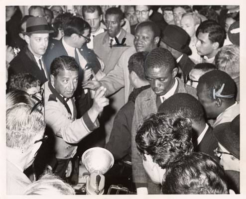 File:Bellboy gesturing to African guests to follow him in the middle of the demonstration outside the Sheraton Palace Hotel March 7 1964 AAK-0901.jpg