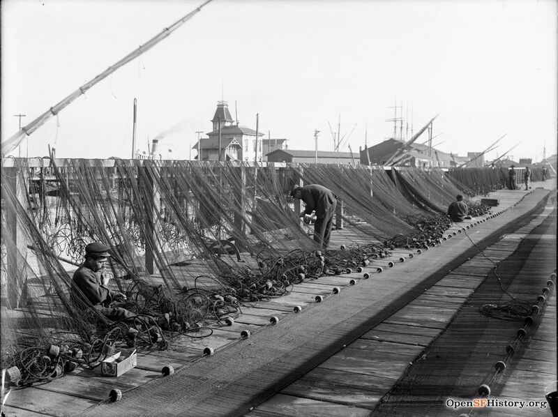 Fishermen mending nets near foot of Powell Street. Meiggs Wharf in the background. c1900 wnp15.708.jpg