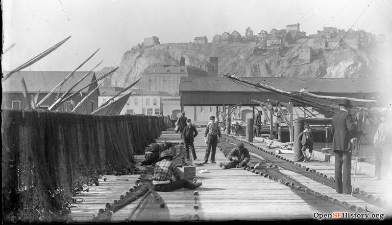 1910 View West from Union Street Wharf (then Fisherman's Wharf) toward Telegraph Hill in background. Men mending fishing nets, boys posing wnp15.1663.jpg