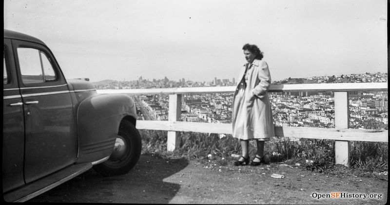 C1950 Woman standing by a car looking from Bernal Heights to downtown. wnp14.3485.jpg